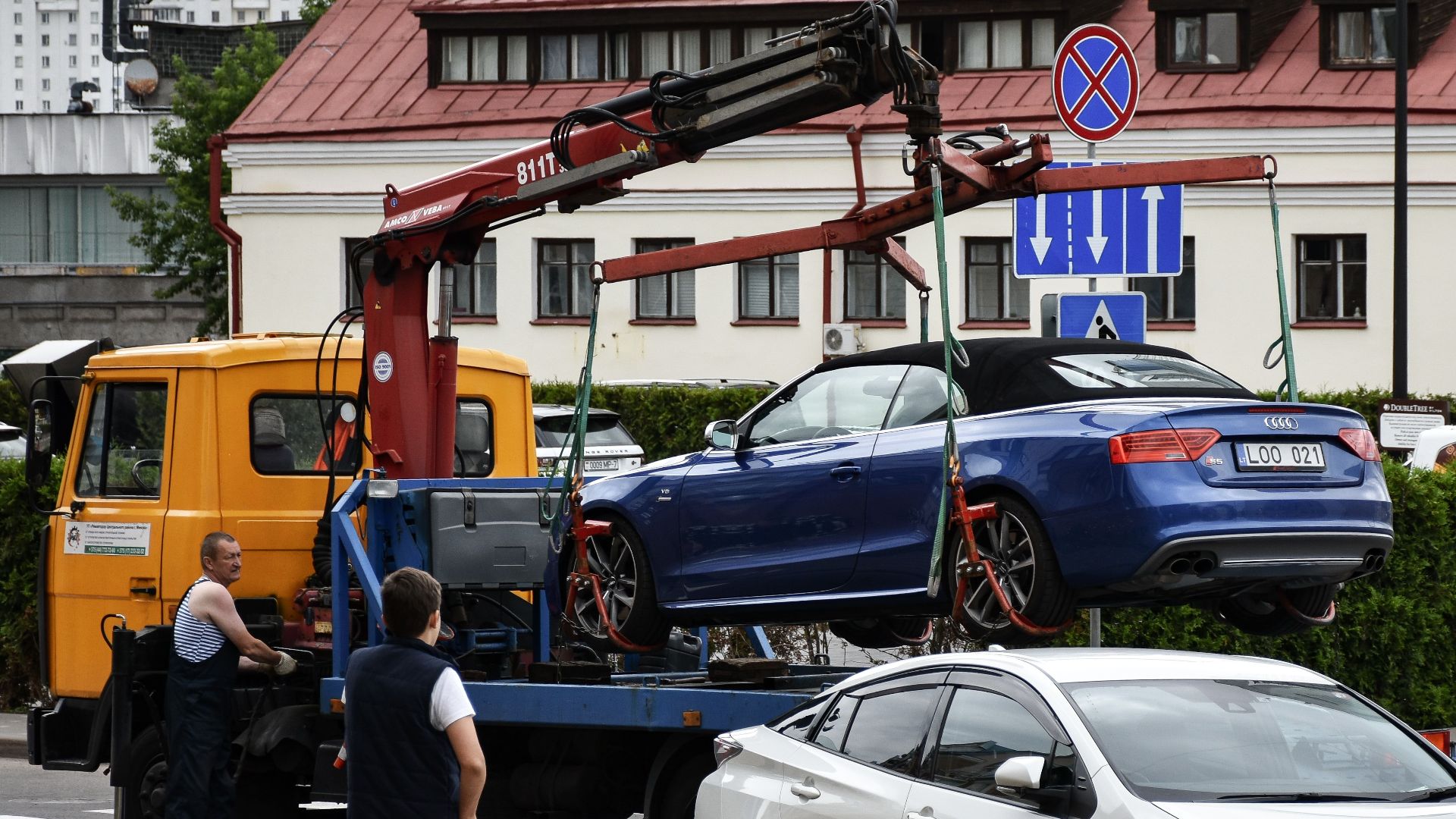 Towing a blue Audi convertible in a bustling city street.
