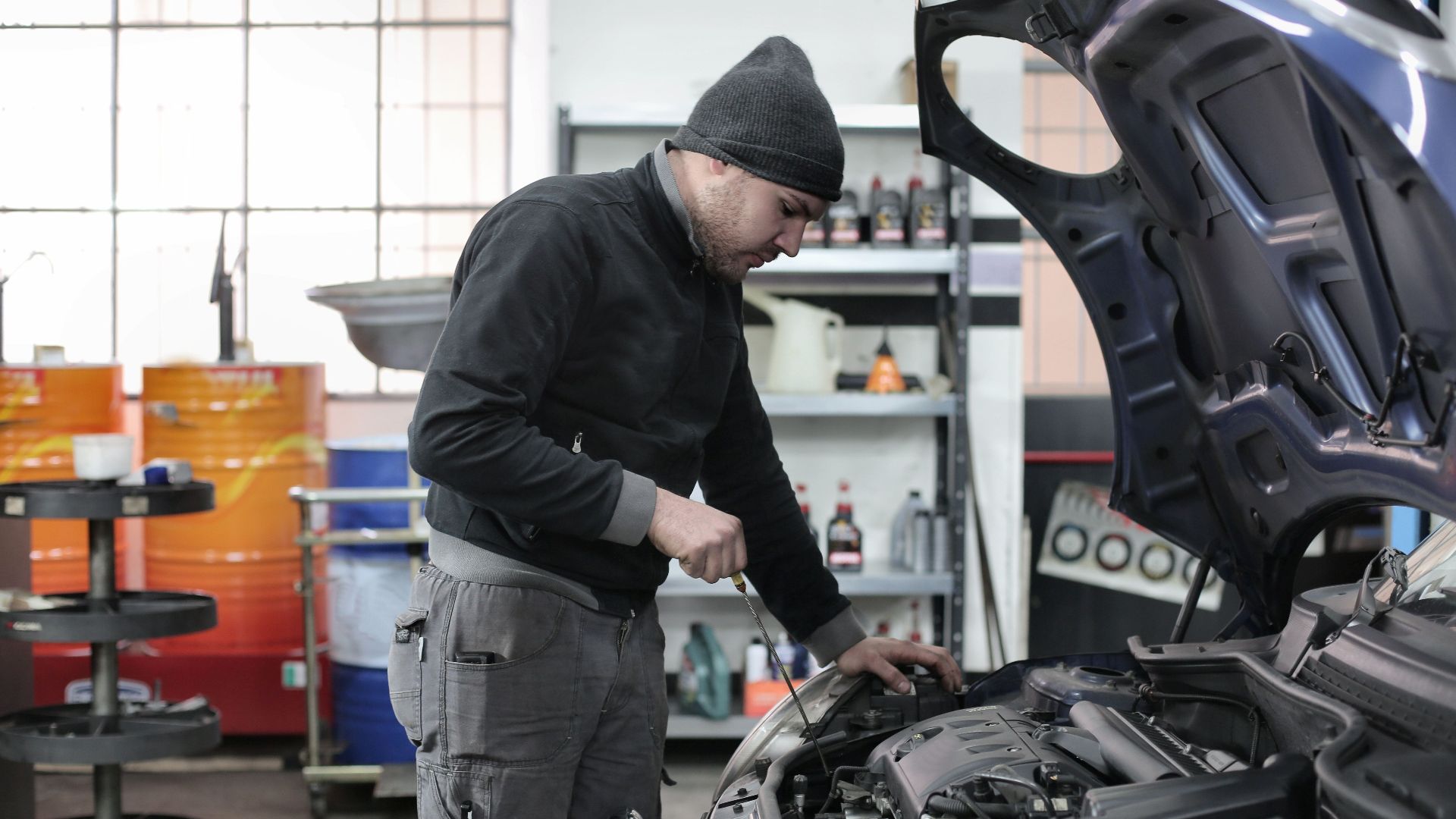 Mechanic checking a car engine in a garage, ensuring quality maintenance and repair.