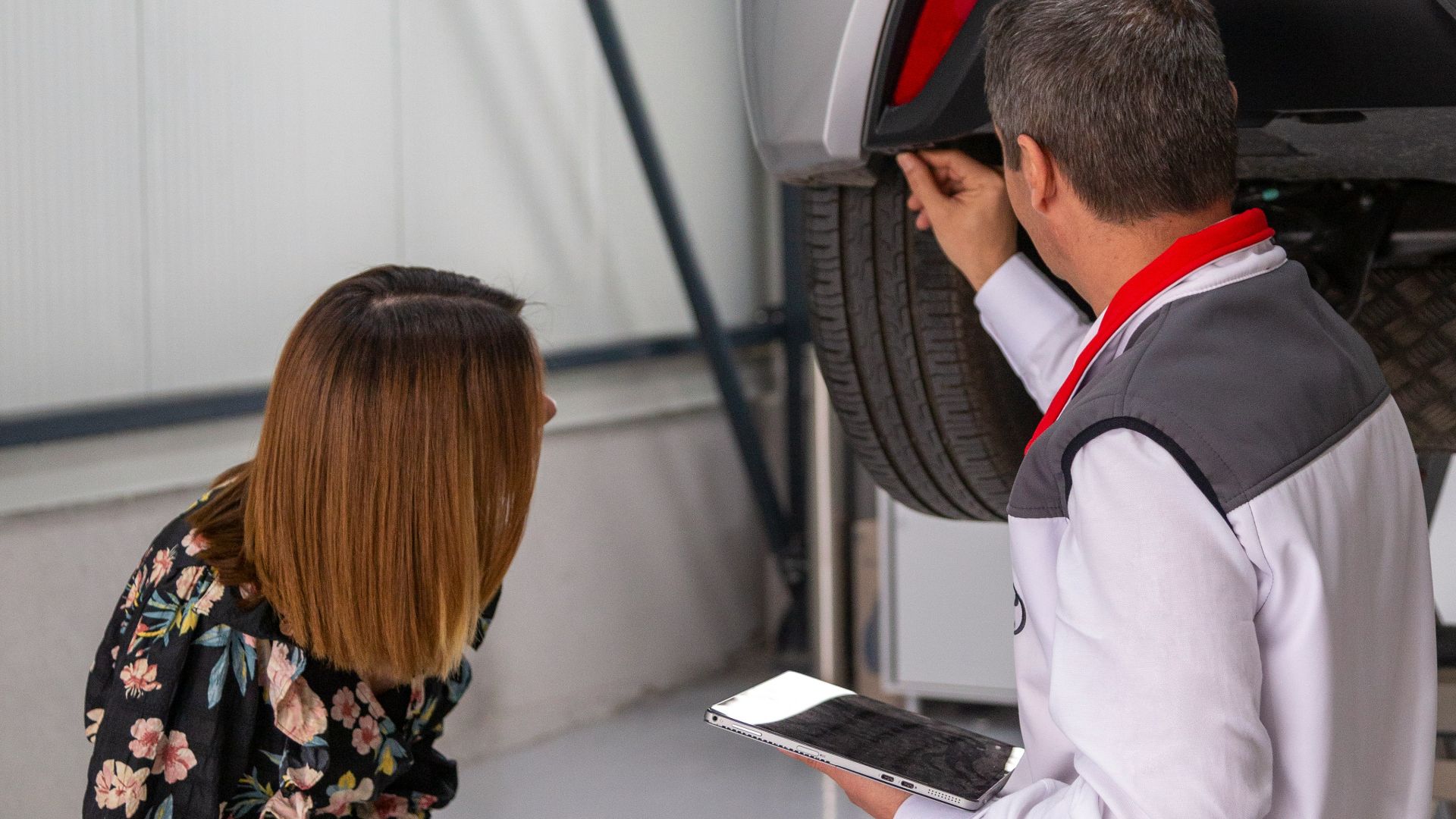 A man and a woman looking under a car
