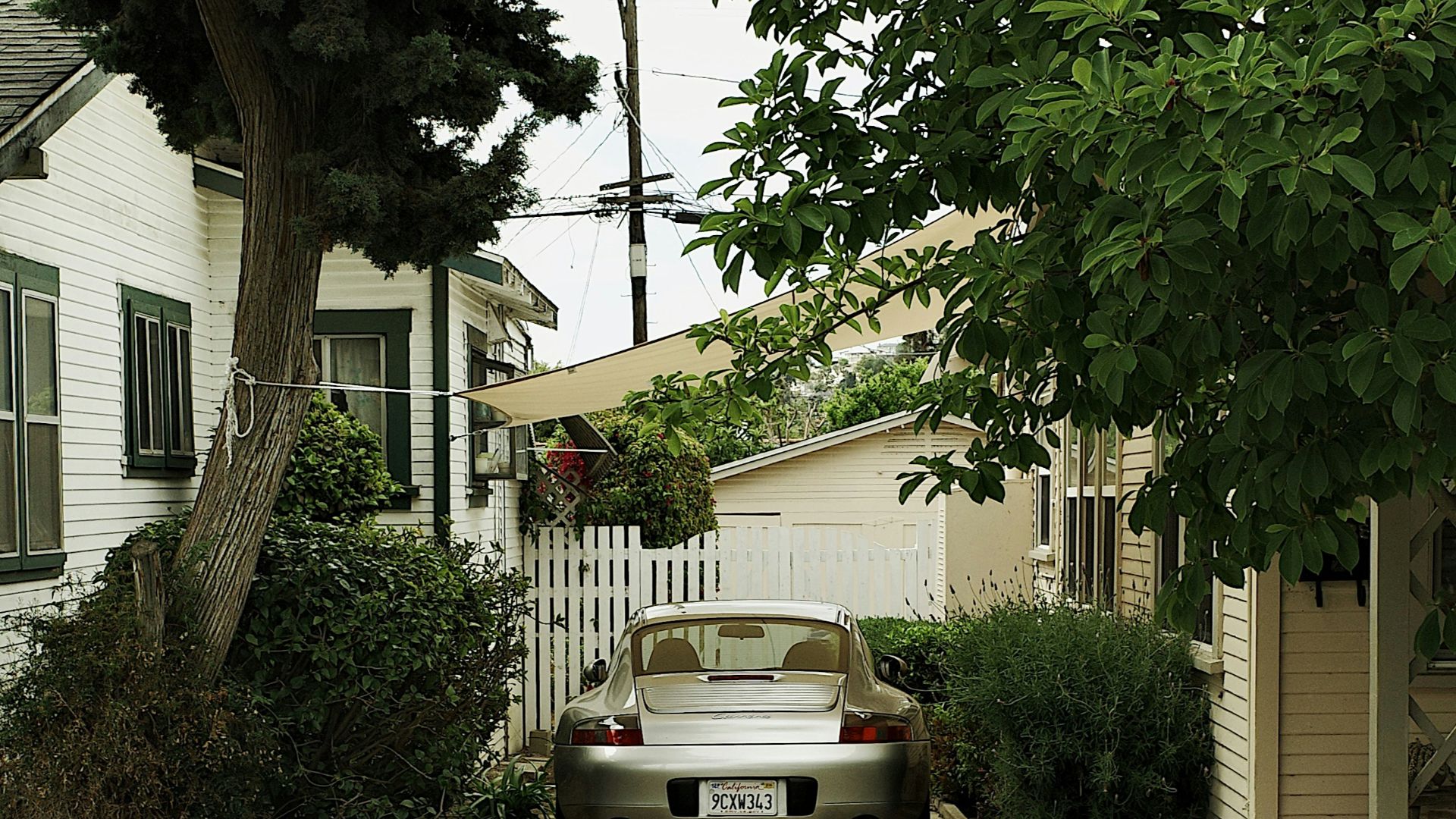 A silver car is parked on a long driveway
