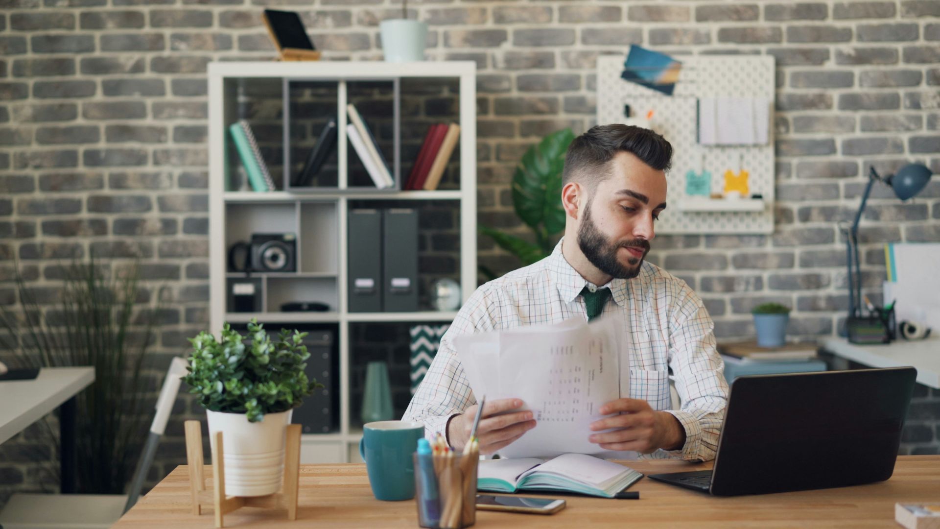 a man sitting at a desk with a laptop and papers
