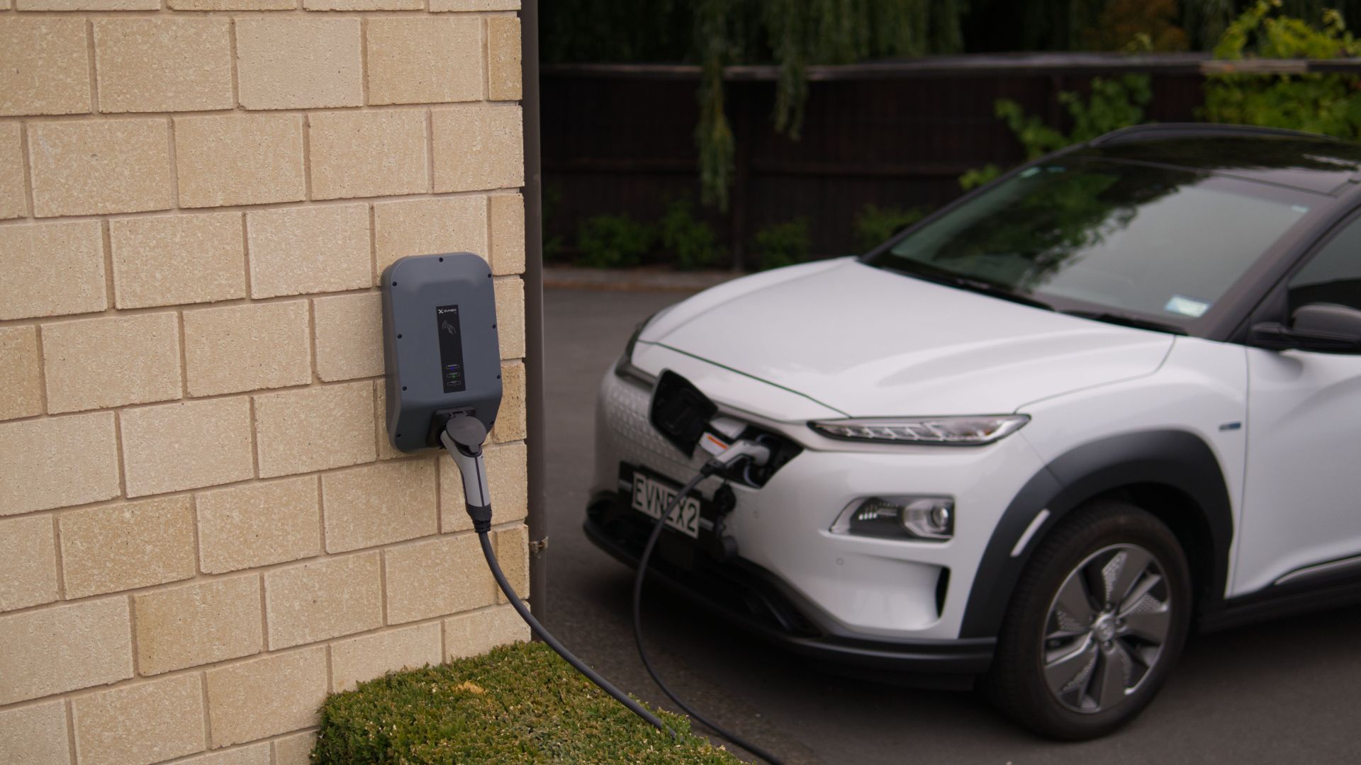 A white electric car charging at a station in Christchurch, New Zealand, showcasing modern eco-friendly transportation.