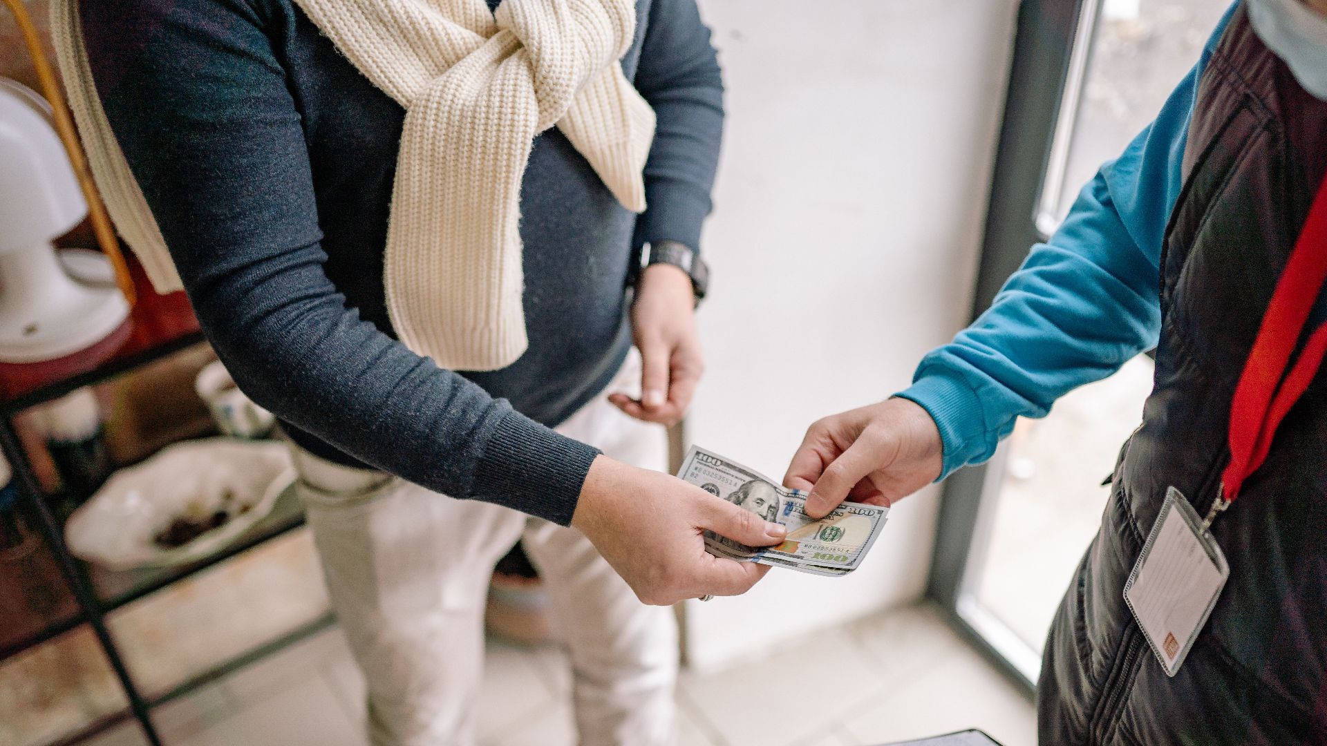 Close-up of hands exchanging cash during a transaction indoors, highlighting payment details.