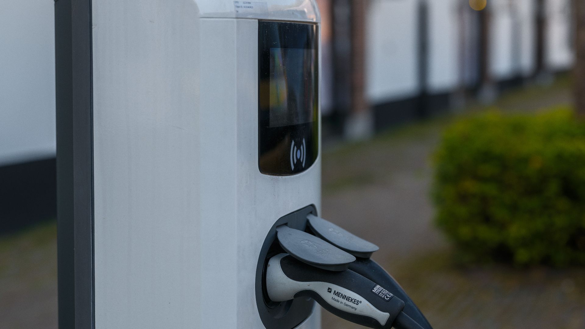 Close-up of an electric vehicle charging station with cable and plug outdoors.