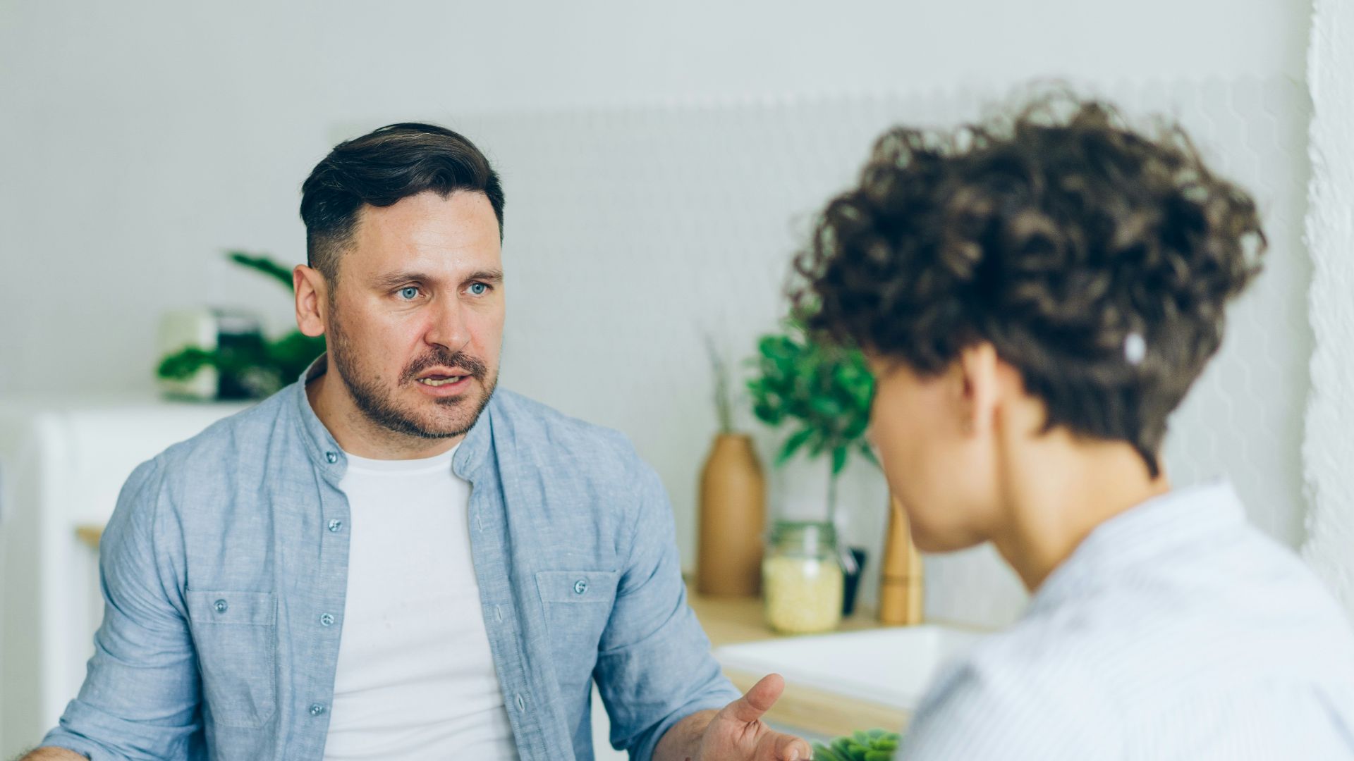a man sitting at a table talking to a woman