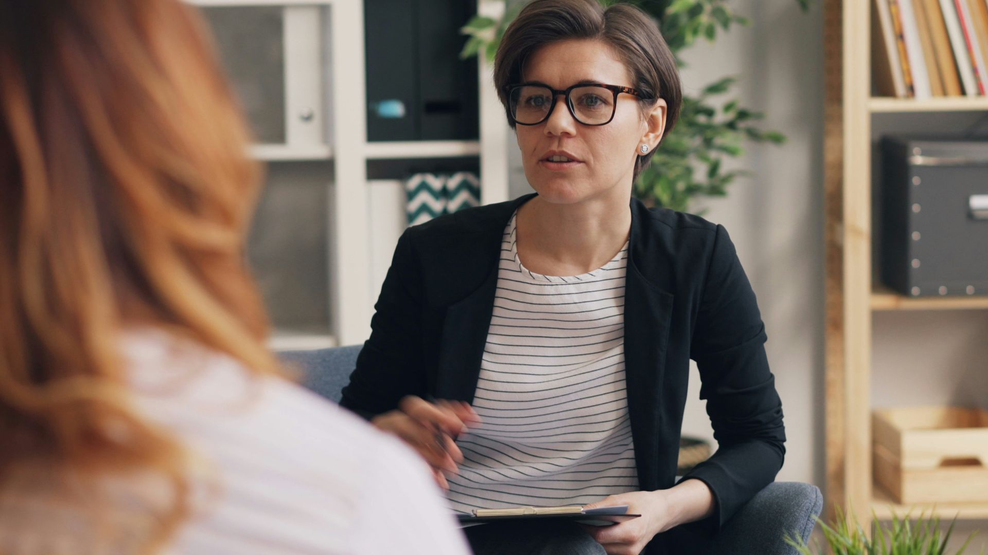 a woman sitting on a couch talking to another woman