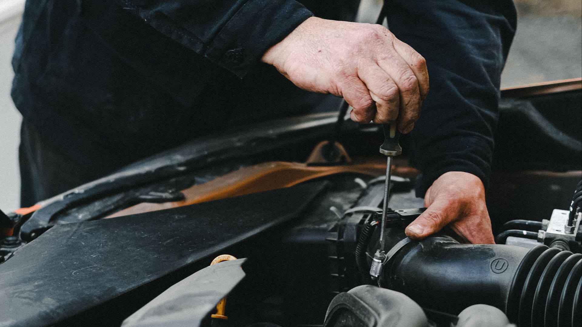 Detailed shot of mechanic working on a car engine showing hands and tools.