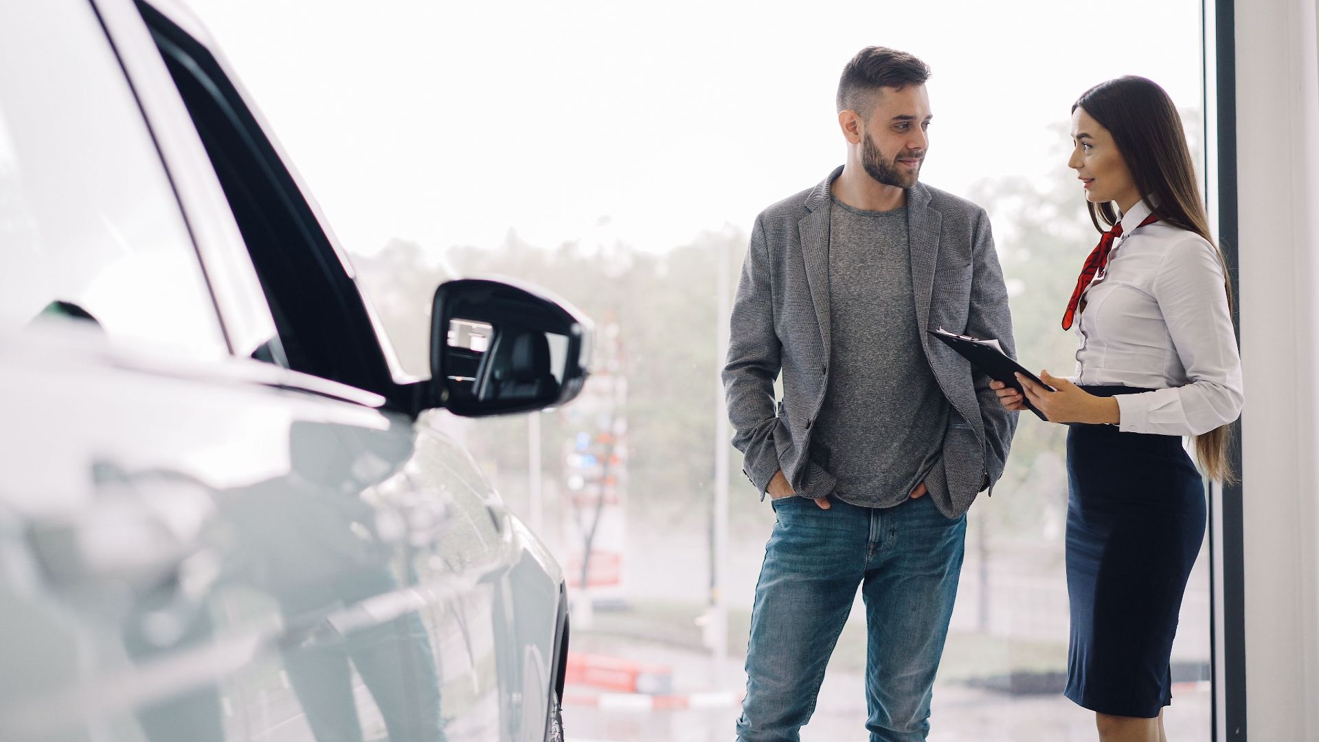 Man consulting with car salesperson in a showroom, discussing car options.