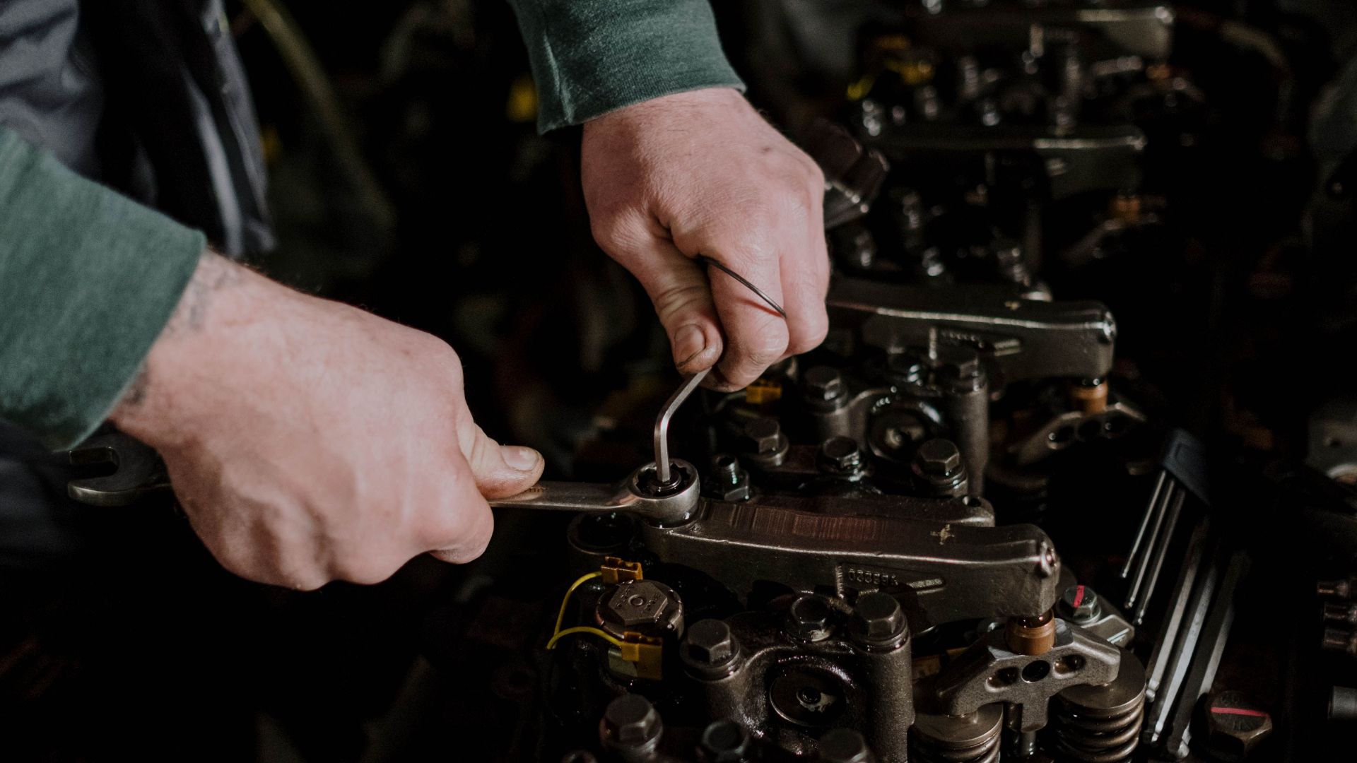Close-up of a mechanic using hand tools to fix an engine, showcasing precision and skill.