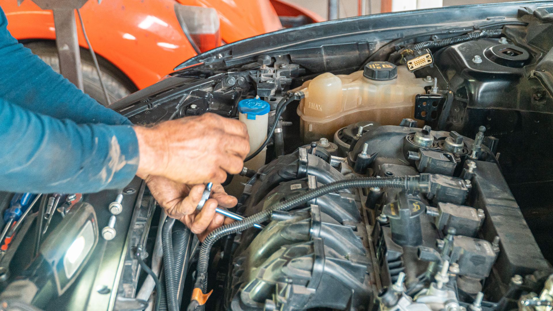 Mechanic's hands repairing a car engine, showing technical precision in an automotive garage.