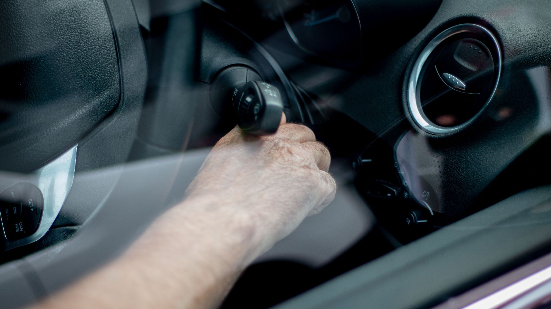 Close-up of a driver's hand starting the car ignition in Leeds, UK.