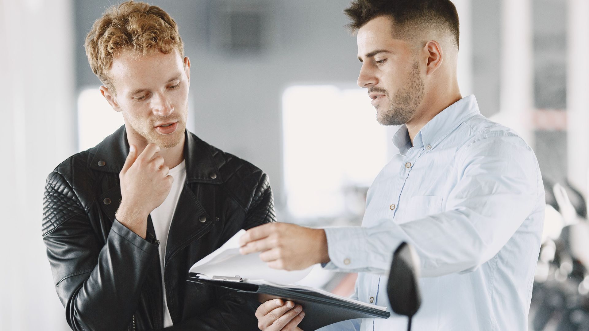 Two adults discussing purchasing options at a motorcycle dealership.