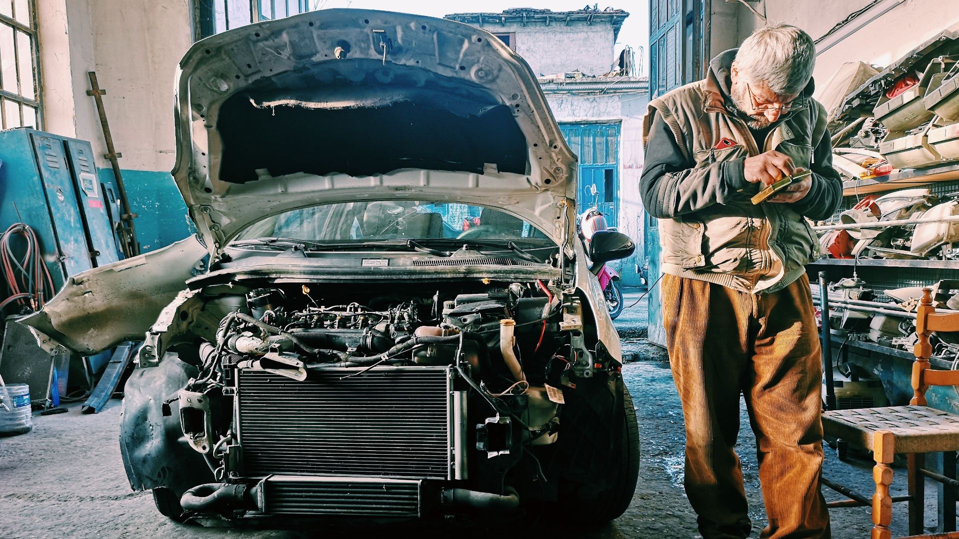 Mechanic repairing car in an auto workshop with the hood open showcasing the engine.