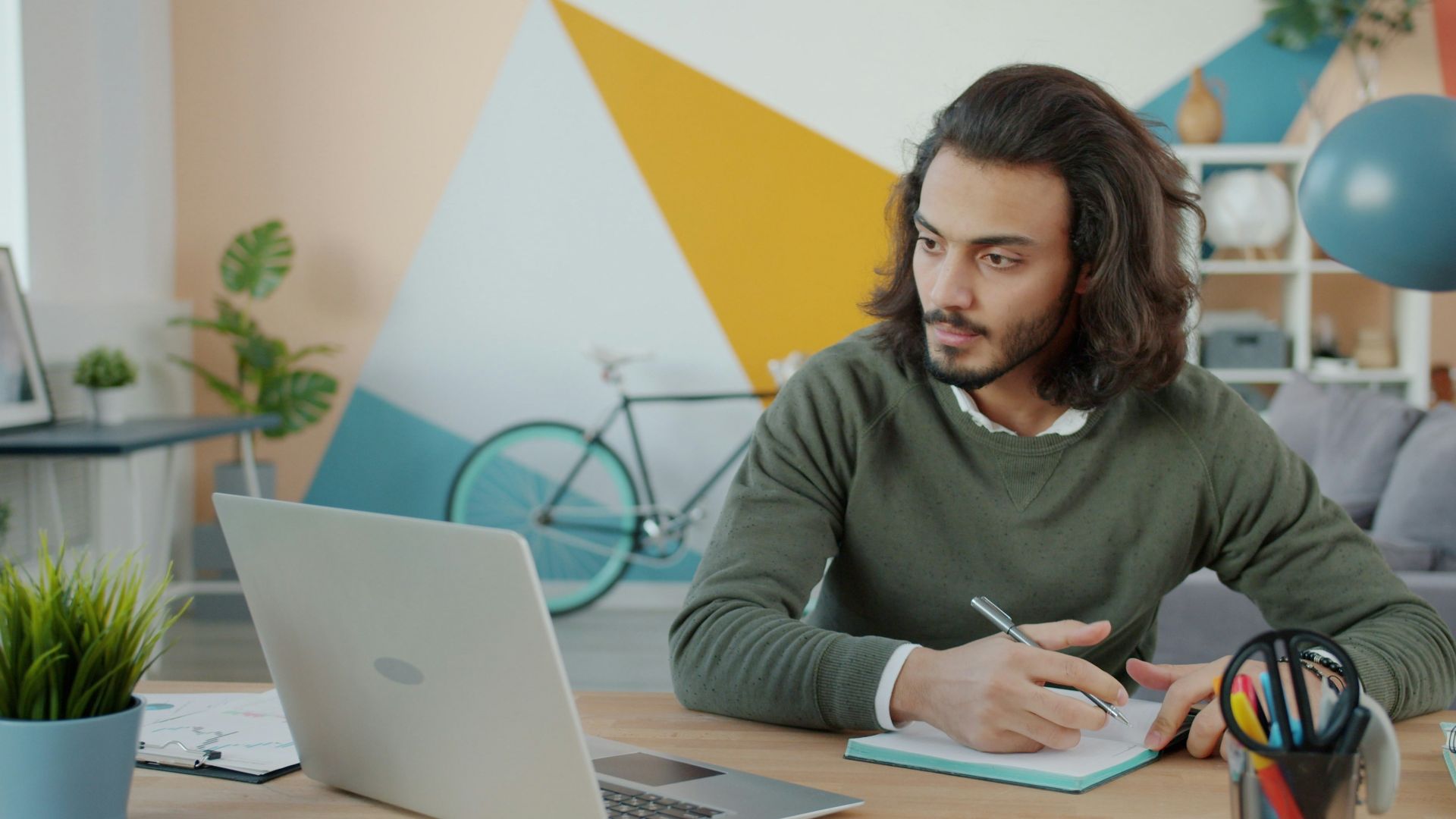 Man working at a desk with a laptop and notebook
