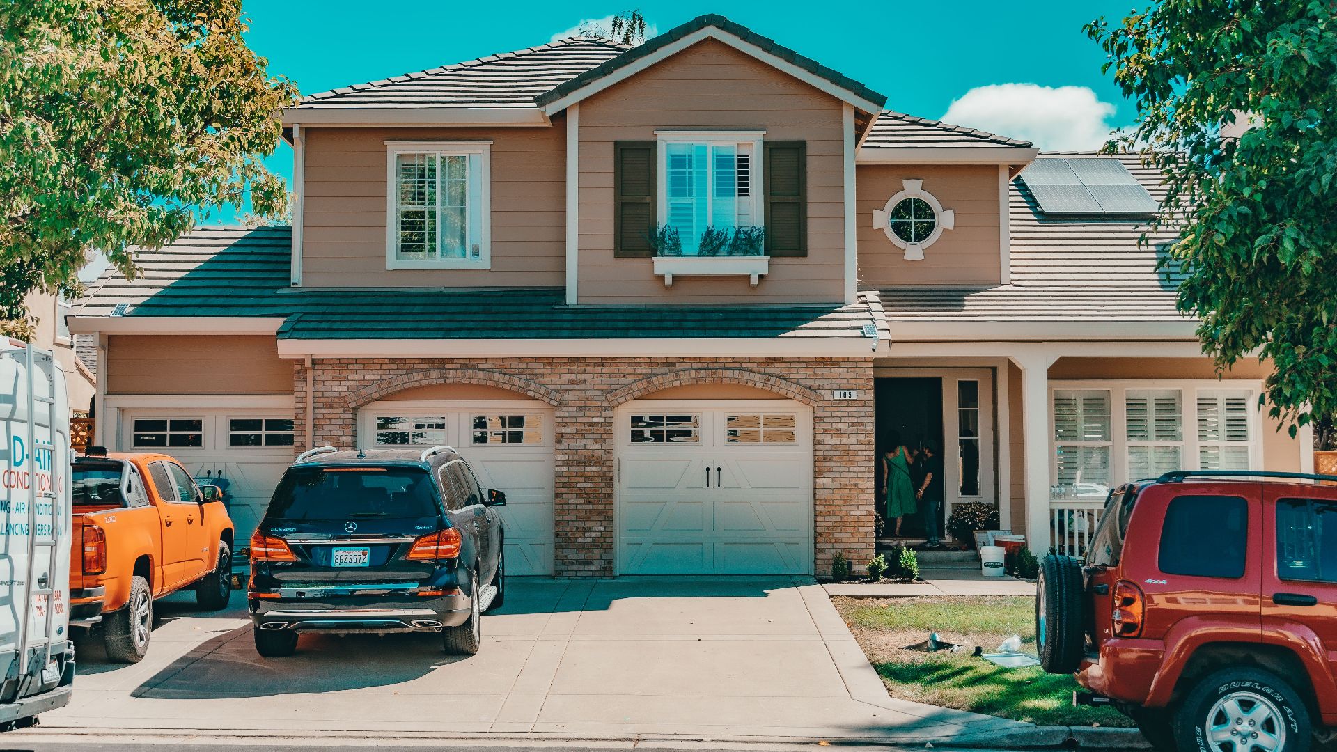 Charming suburban house with parked cars and vibrant summer setting.
