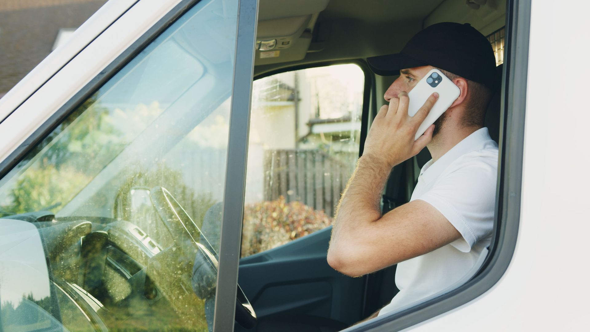 A man in a vehicle making a phone call, showcasing modern communication.