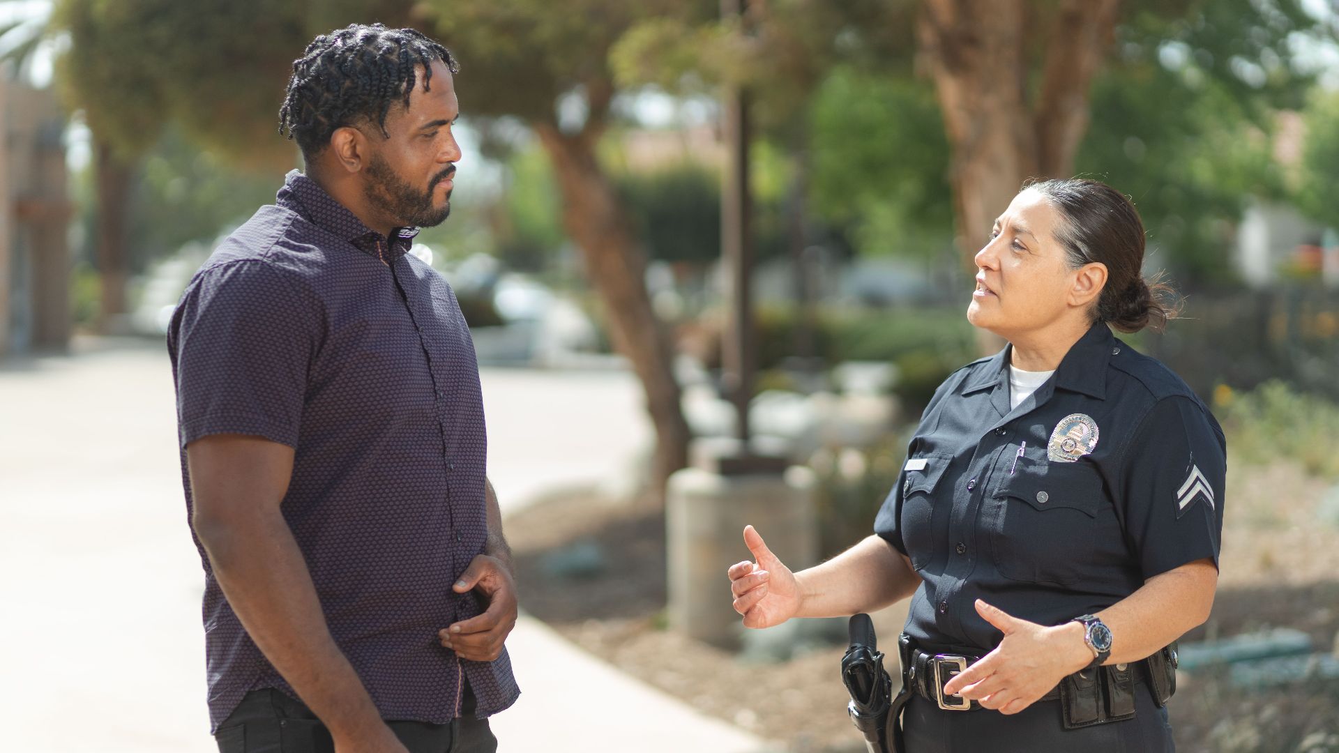 A police officer engaging warmly with a community member outdoors on a sunny day.