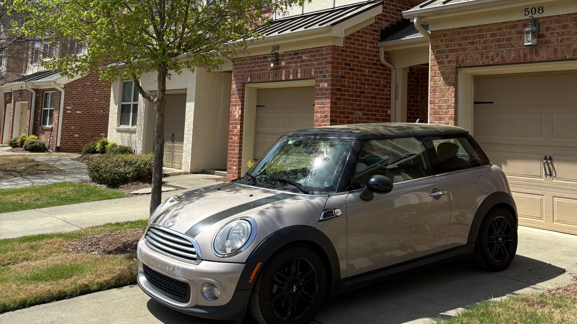 A stylish car parked in front of a suburban home on a sunny day.