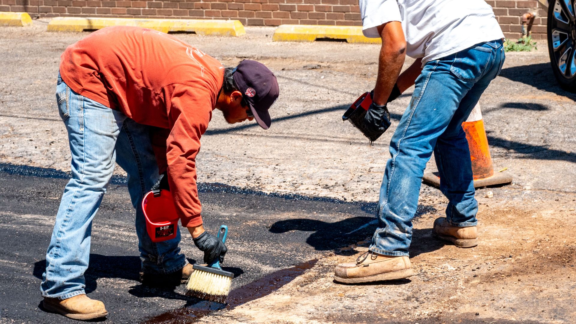 Two workers engaged in asphalt repair on a sunny day in Amarillo, Texas.