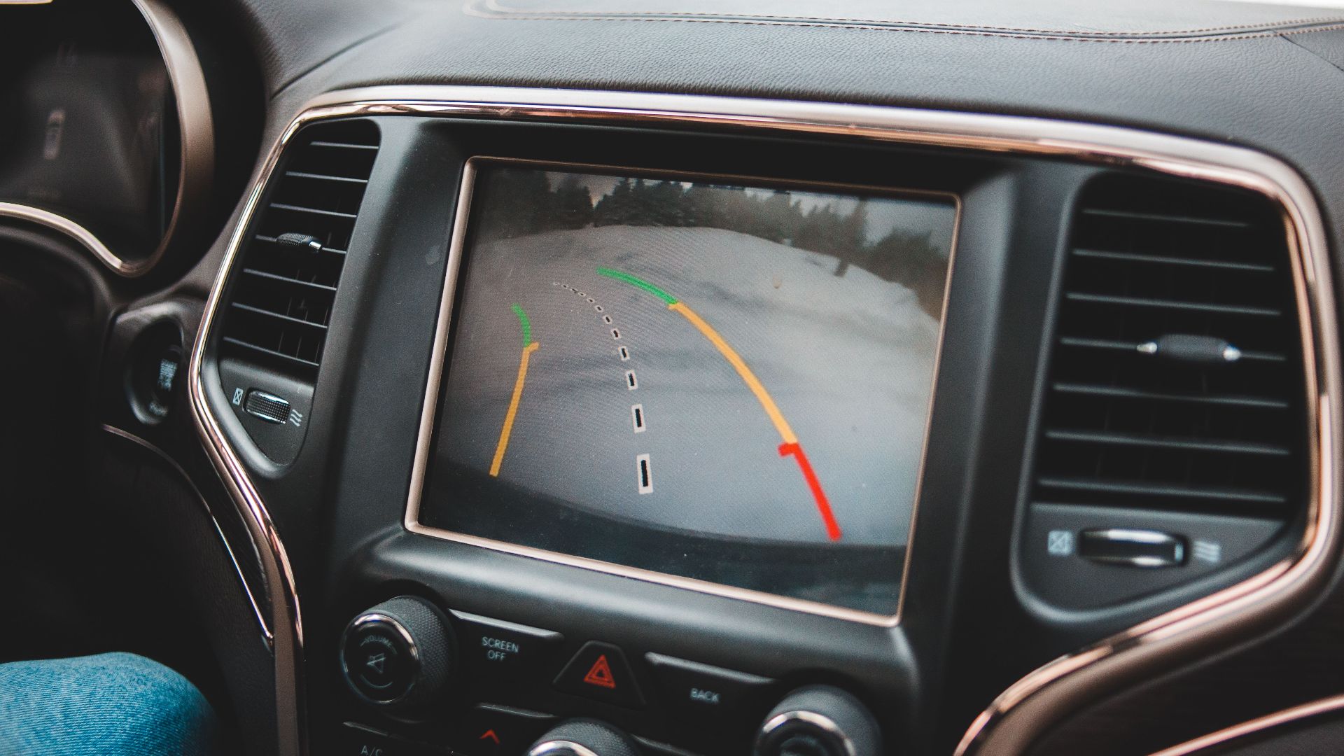 Close-up of a car's dashboard showing a rearview camera display for parking assistance.