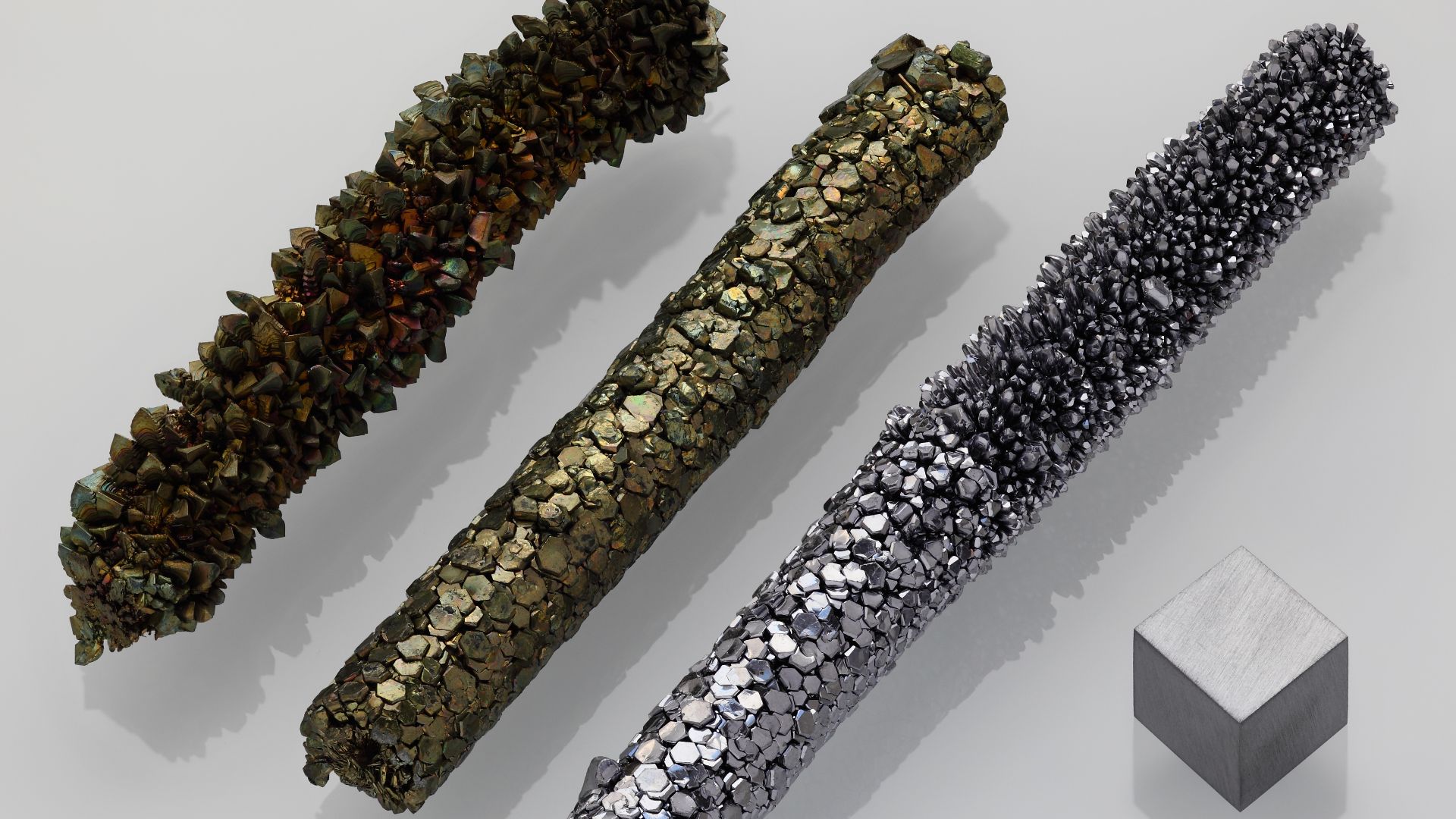 Purest Vanadium 99.9%, three samples of a crystal bar showing different crystal textures and an on air greenish oxidized surface, made by crystal bar process (from the collection of Ethan Currens), as well as a highly pure (99.95% = 3N5) 1 cm3 vanadium cu
