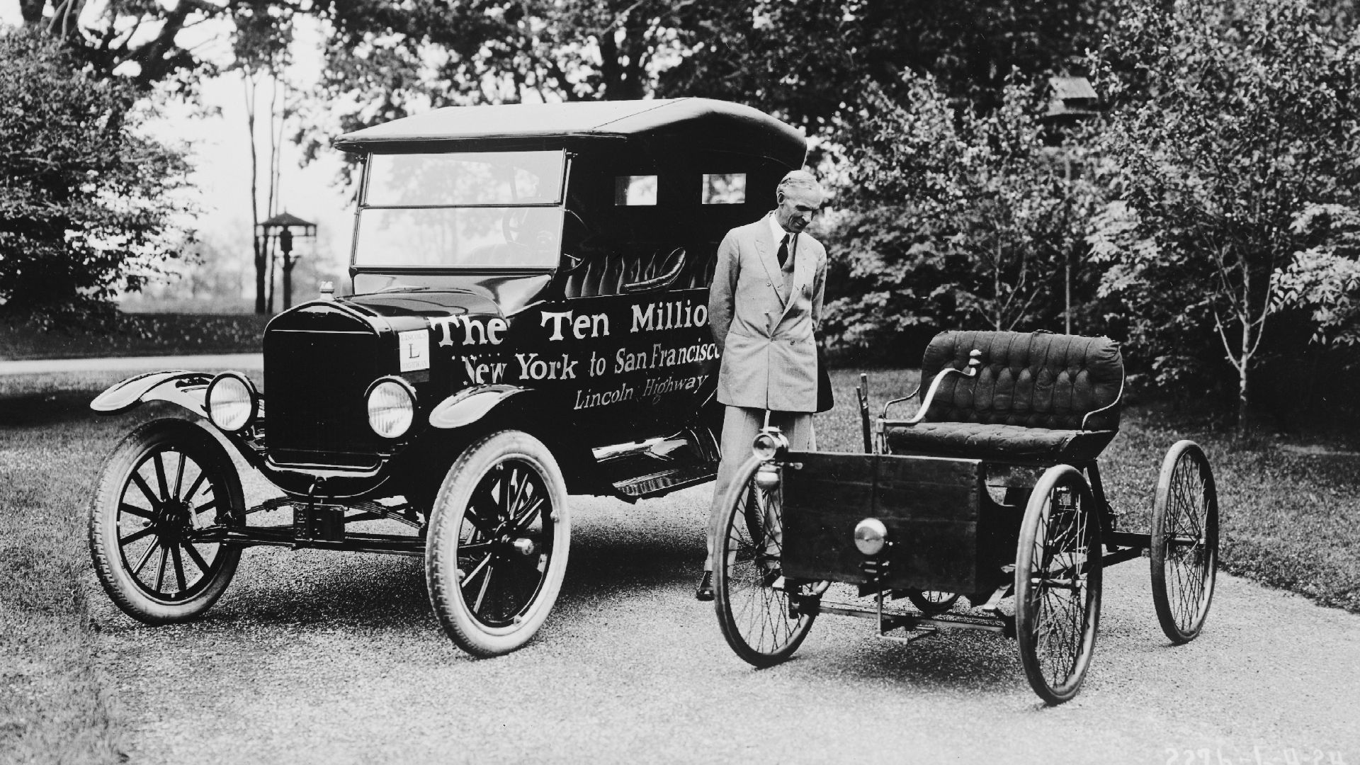 Henry Ford standing between the ten millionth Model T produced and a Ford Quadricycle