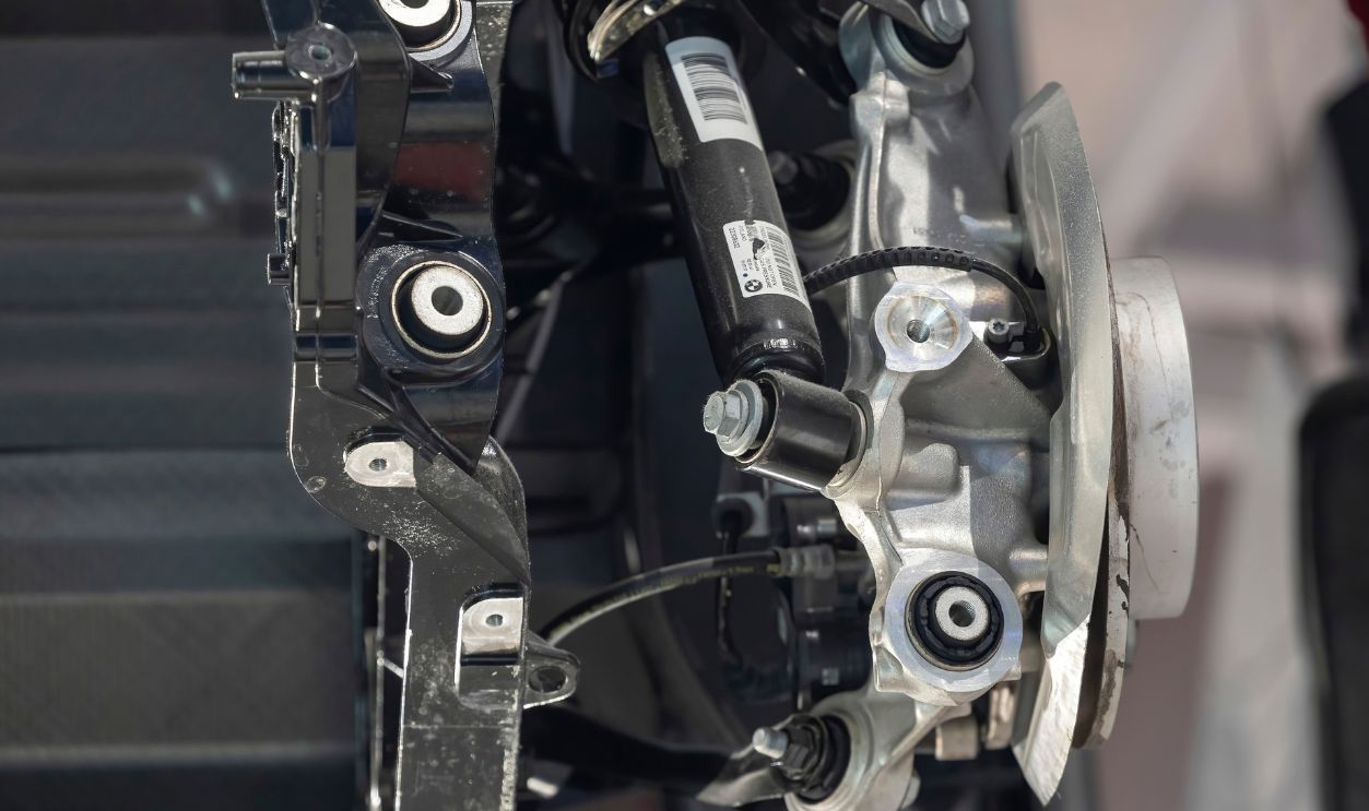 Shutterstock - 2719837797 -  Close-up of a BMW i3 rear suspension and brake assembly showing shock absorber, control arms, hub, and mounting points in a museum display.