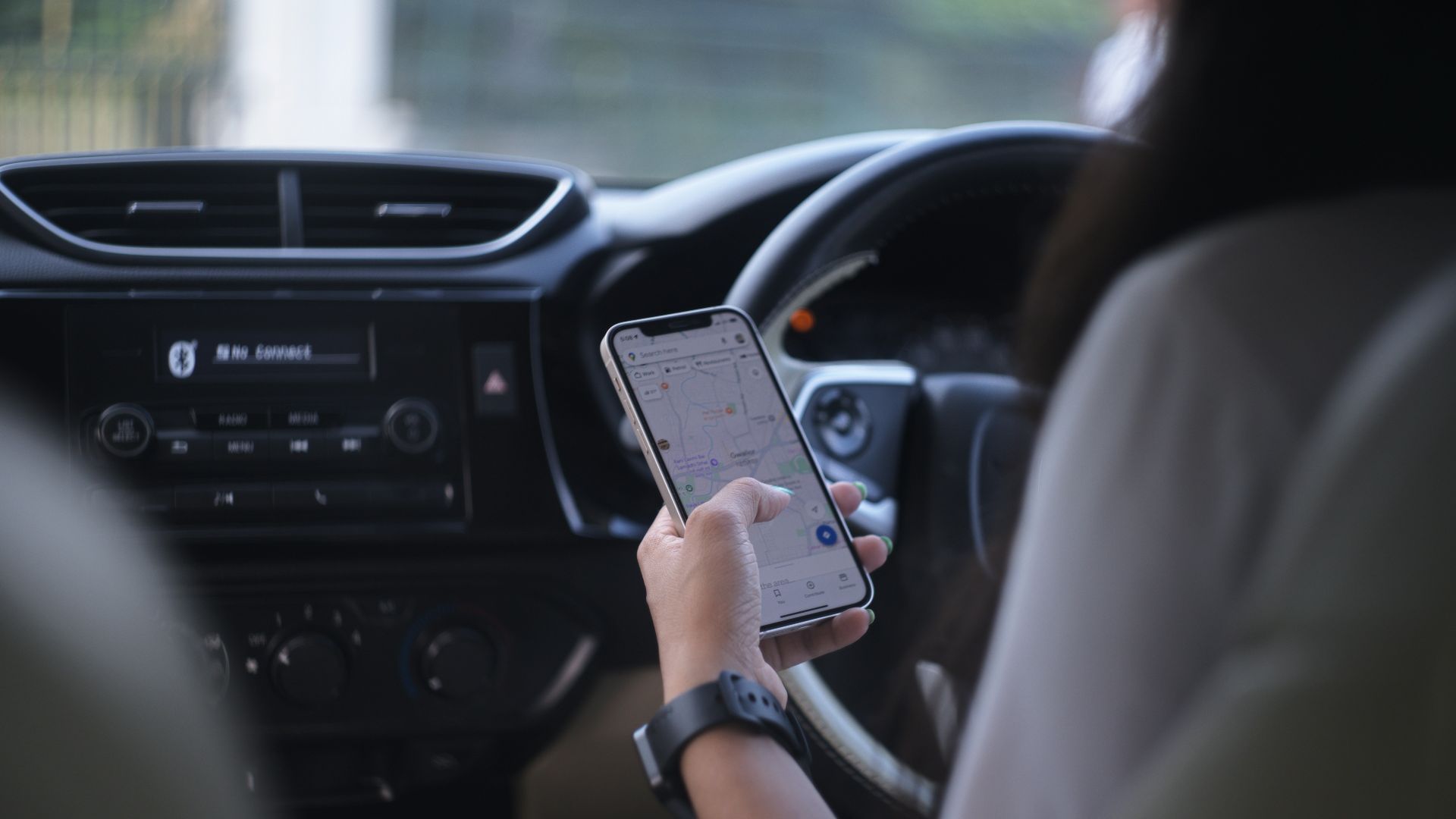 A woman holding a cell phone while driving a car