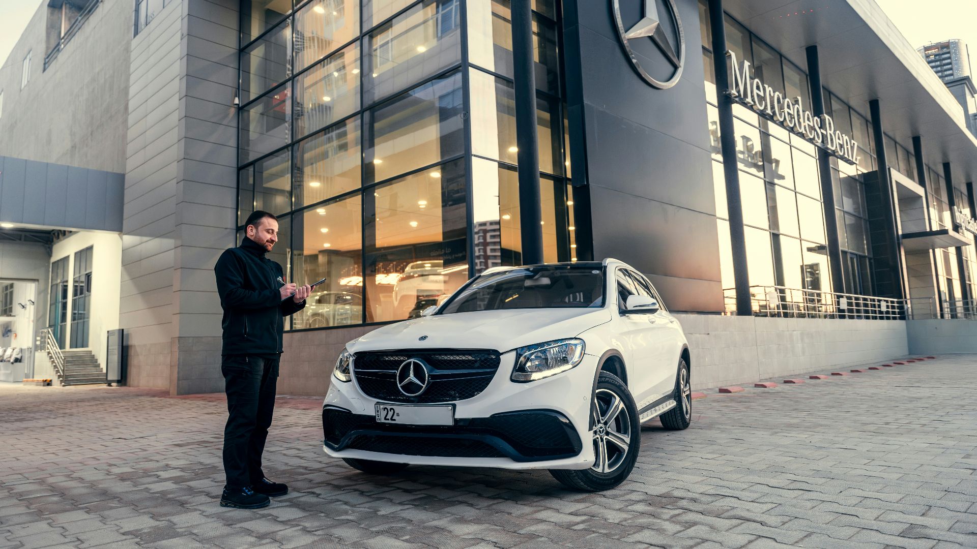 Man standing by a white mercedes-benz suv outside dealership