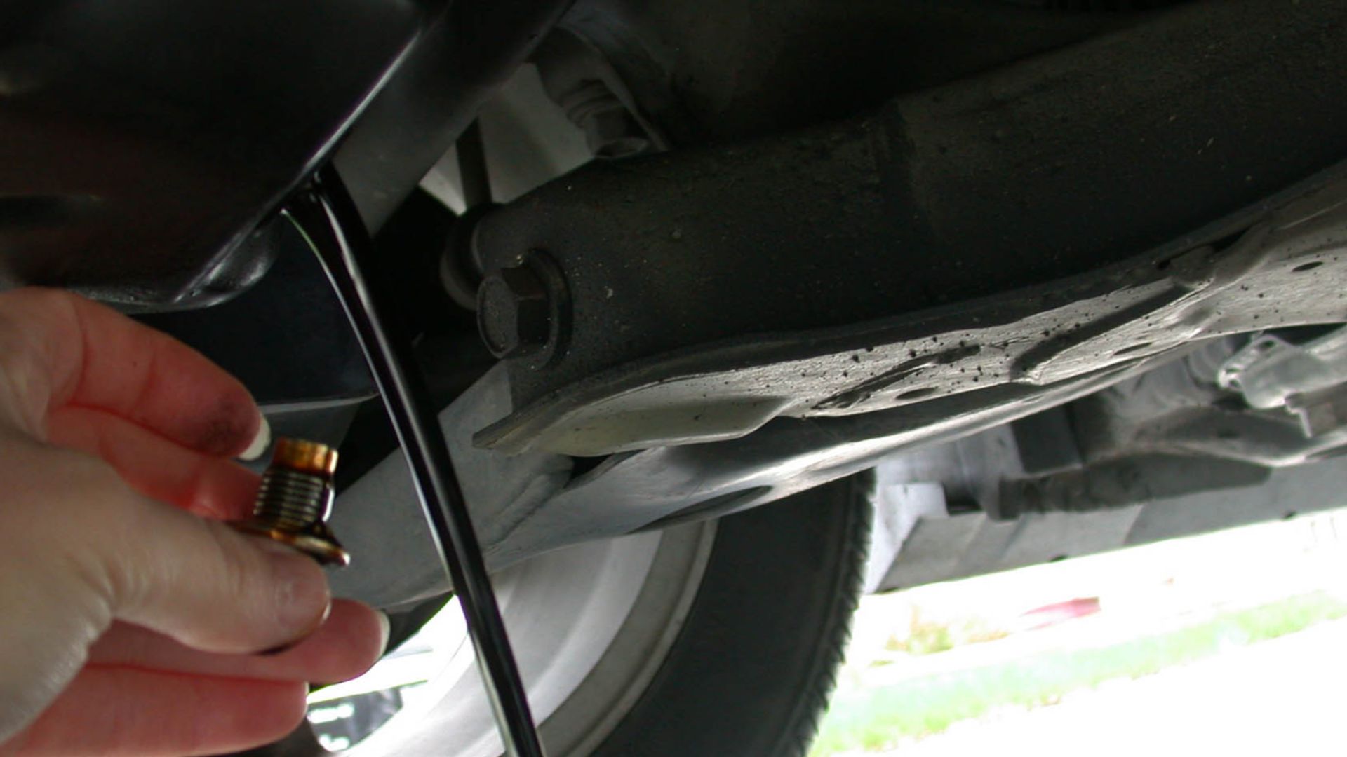Draining the motor oil out of an automobile as part of an oil change.