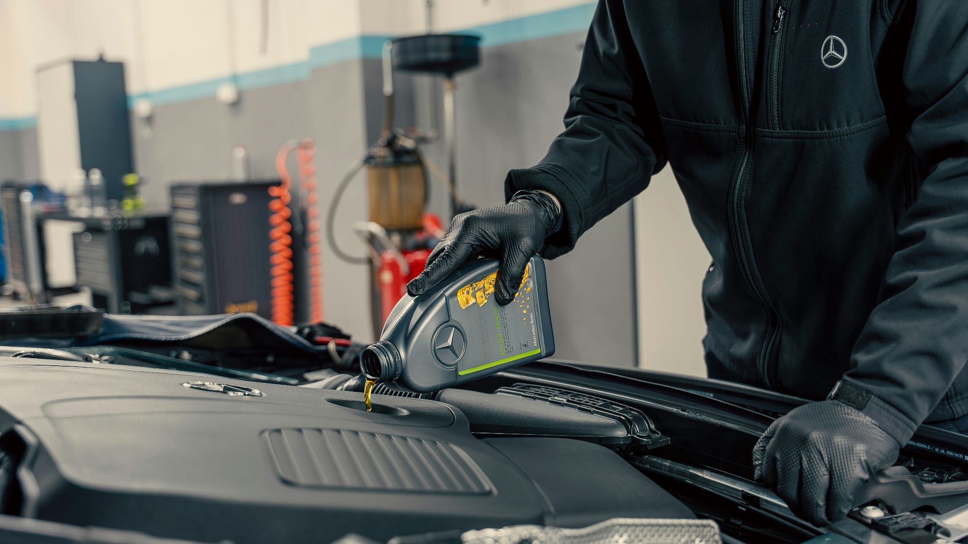 Mechanic pouring oil into car engine