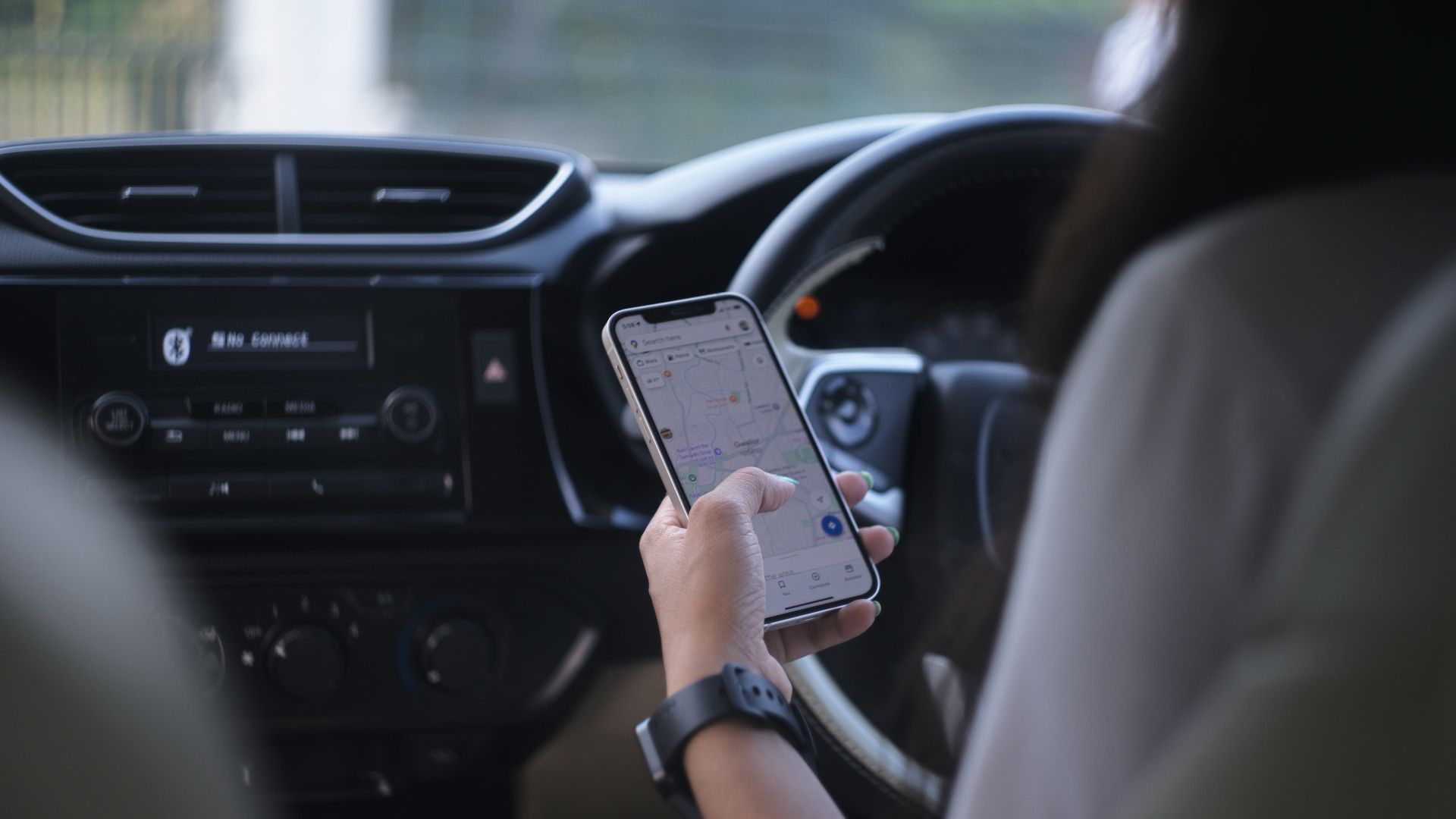 A woman holding a cell phone while driving a car