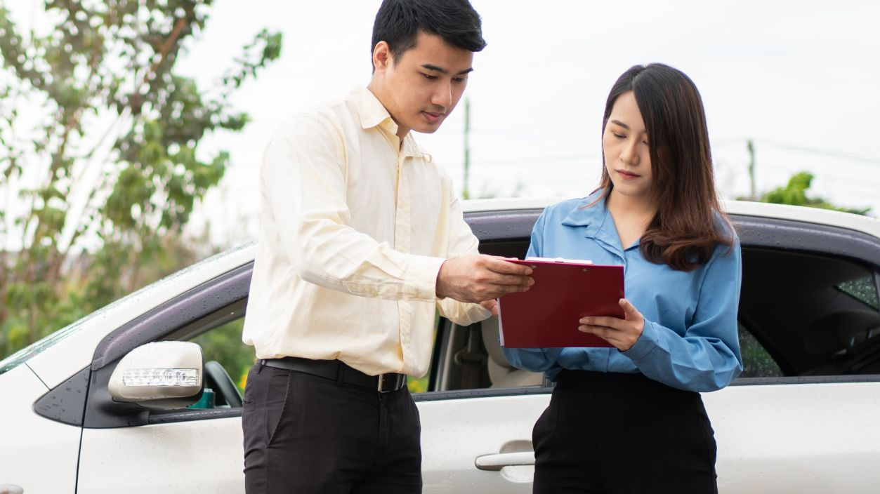 Shutterstock-1991978117, Asian women driver Talk to Insurance Agent for examining damaged car and customer checking on report claim form after an accident. Concept of insurance and car traffic accidents.
