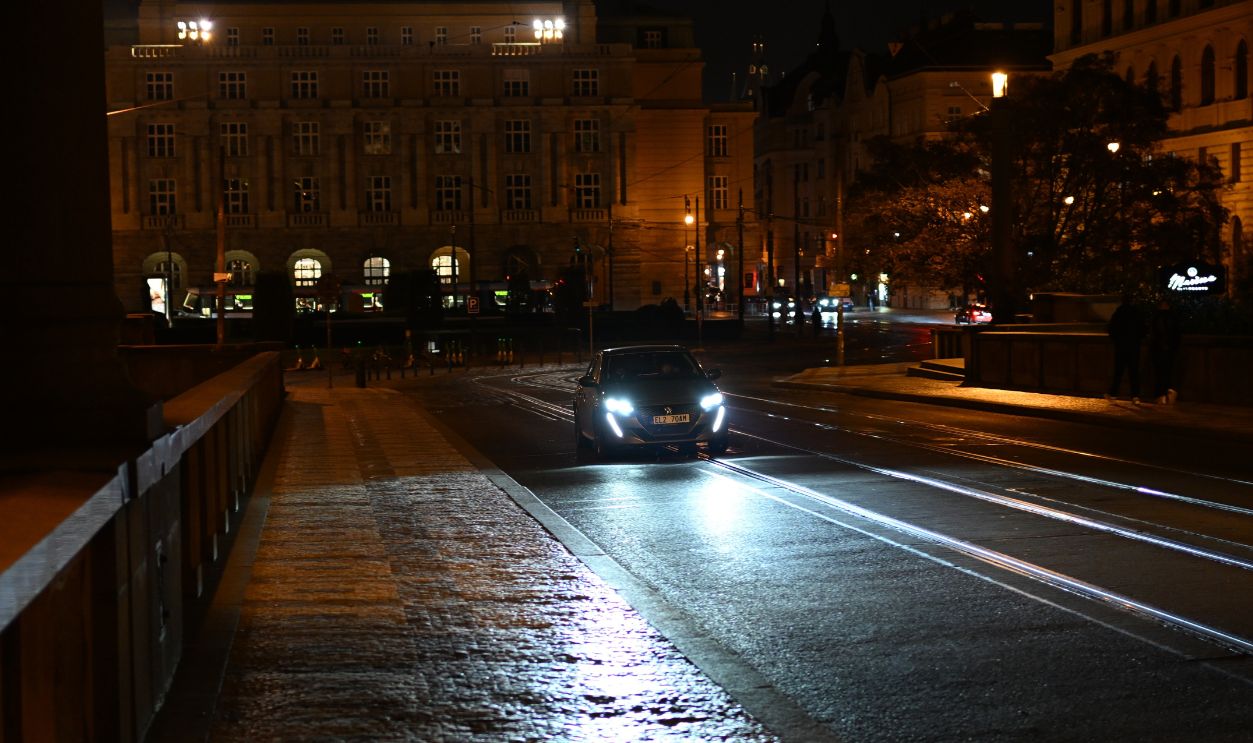 Car with headlights on driving over tram tracks at night in central Prague. October 1, 2025, Czech Republic