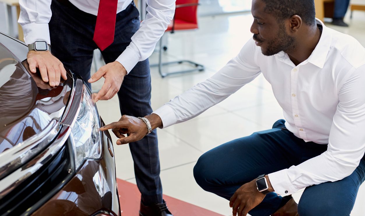 Shutterstock-1784670653, black customer man asks questions about headlights of car in dealership. affable consultant help him with choice