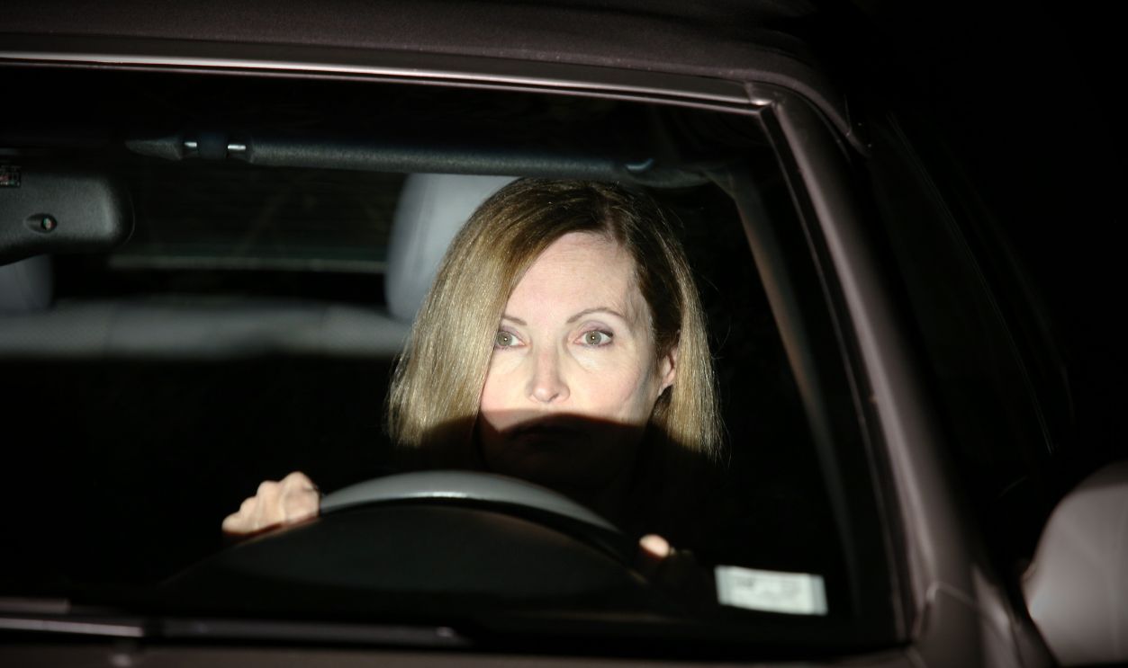 Shutterstock-1138128059, A woman is driving at night; the headlights from the oncoming car are lighting her face.