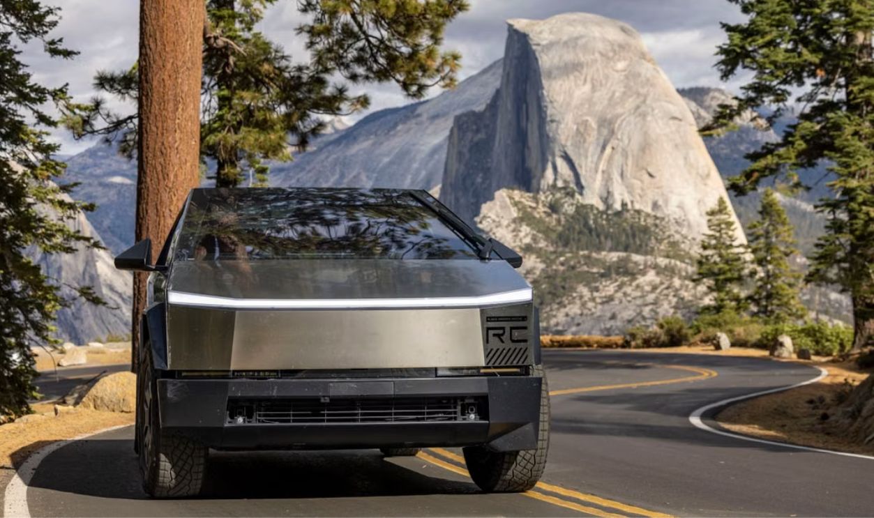 Futuristic vehicle on a winding road with mountain and trees, showcasing modern transportation in nature.