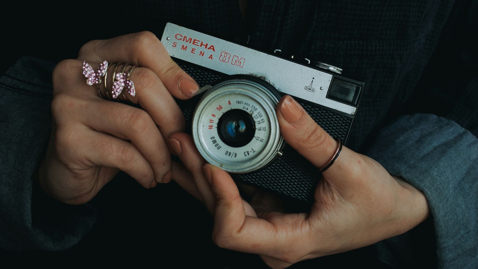 Hands holding vintage camera with butterfly rings