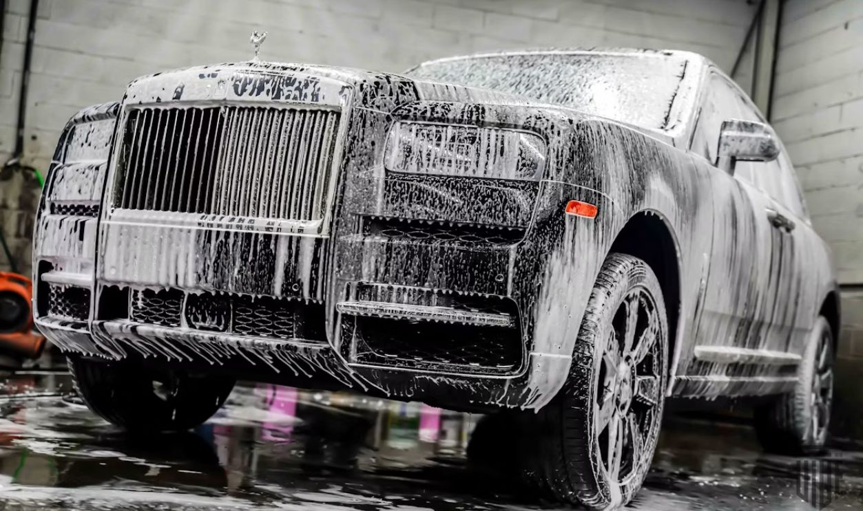 A luxury car covered in white soap suds during washing