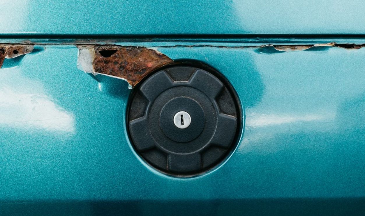 Close-up of a retro car with rust and fuel cap, highlighting nostalgia.