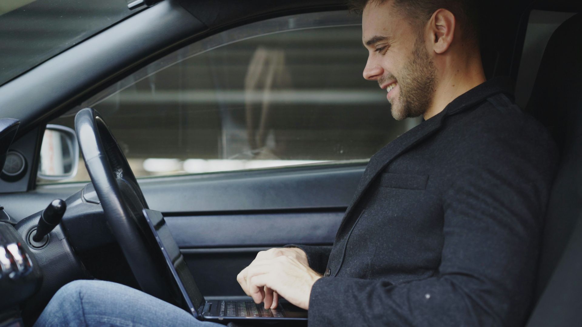 Man working on laptop inside a car