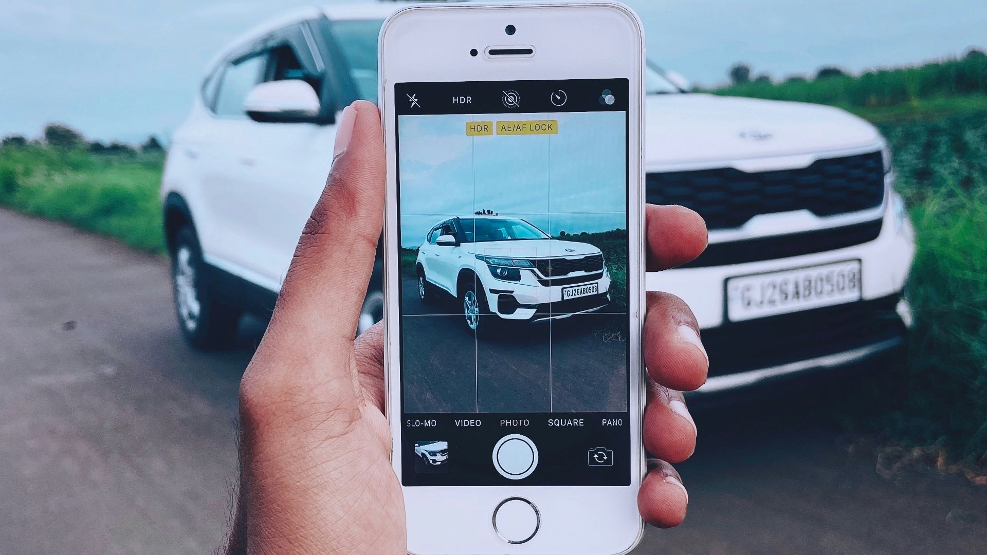 person holding silver iphone 6 taking photo of white car on road during daytime