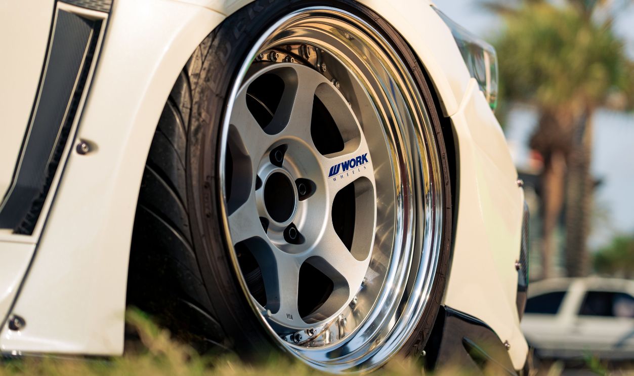 Detailed shot of a sleek car wheel featuring a chrome Work Wheels rim, outdoors
