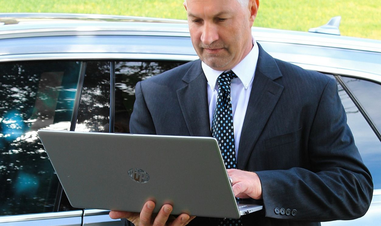 Man using Laptop Beside Car
