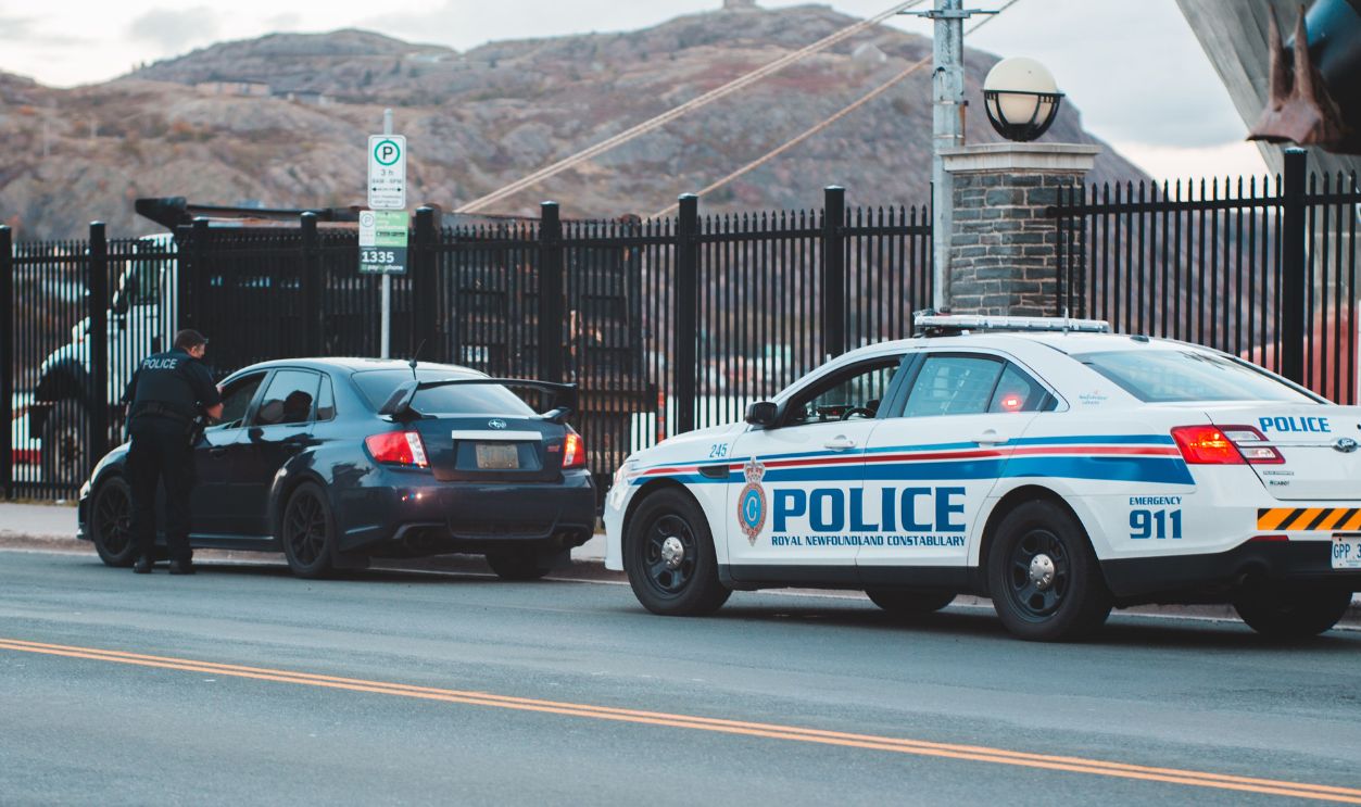 Police officer conducting a traffic stop on a city street with patrol car and sedan