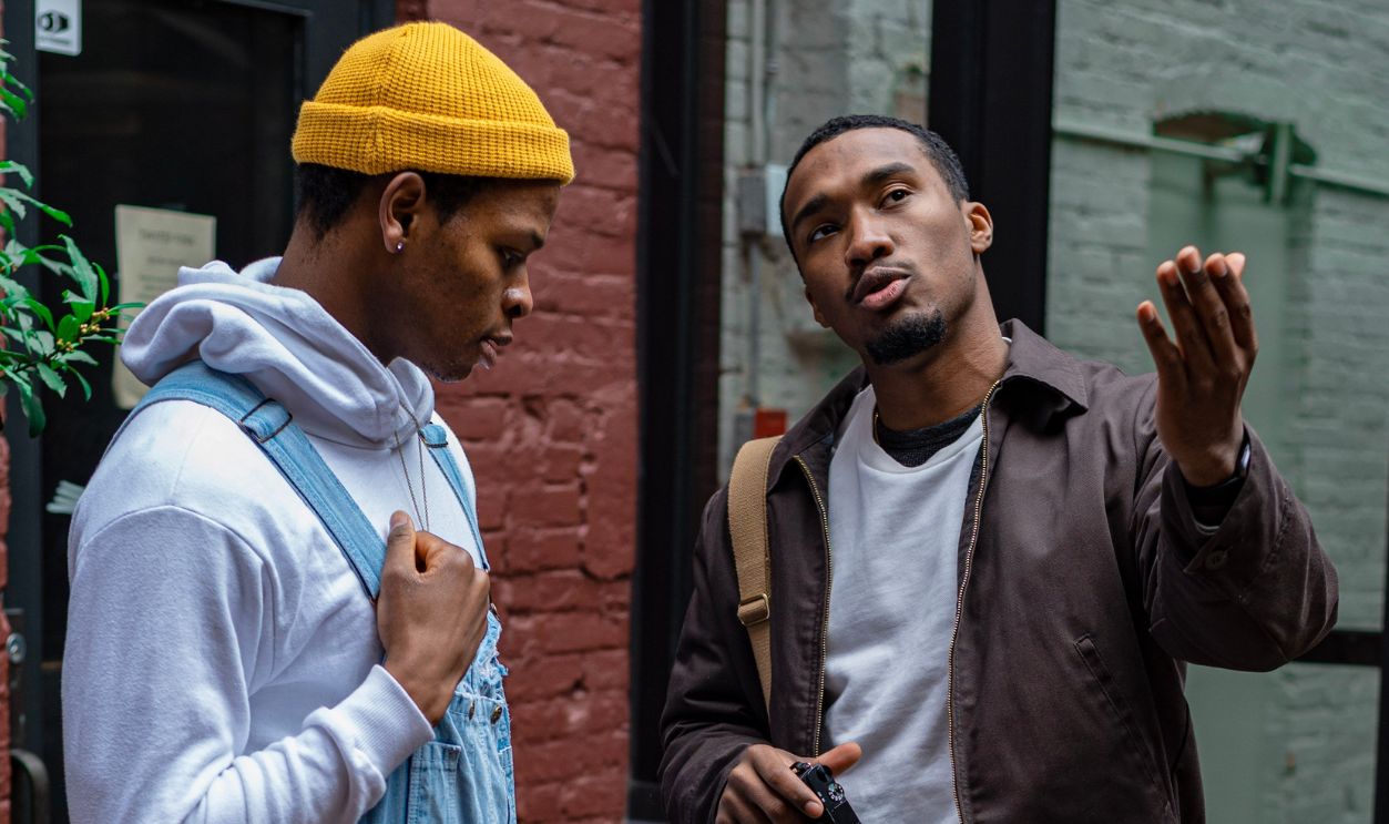 Two men discuss photography techniques outdoors with a camera in hand