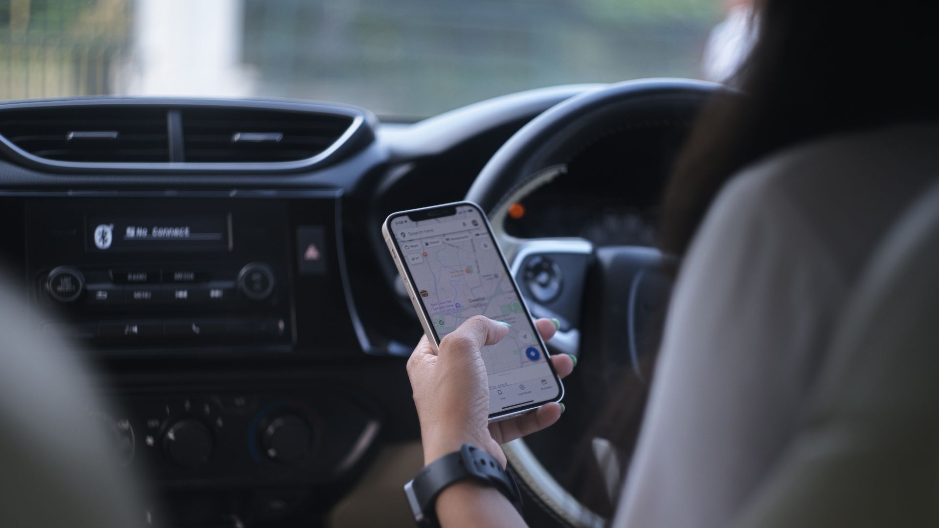 A woman holding a cell phone while driving a car