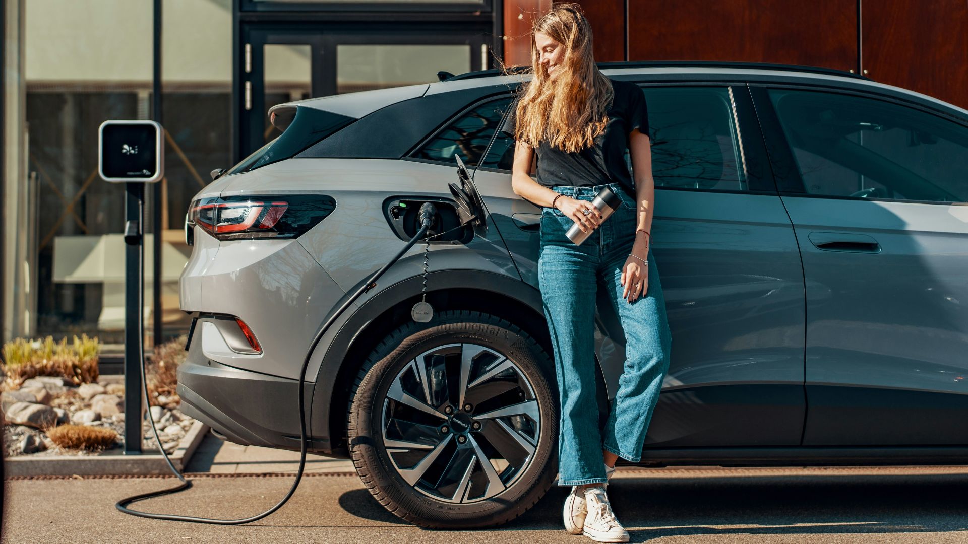 a woman standing next to a blue car