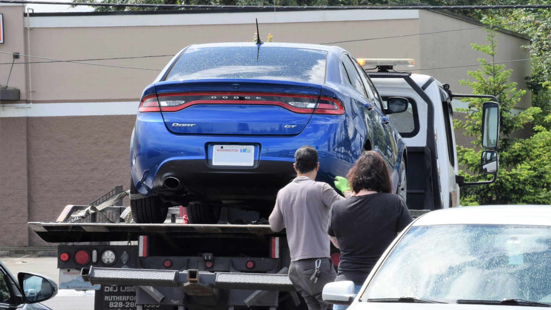 a blue car being loaded onto a flatbed truck