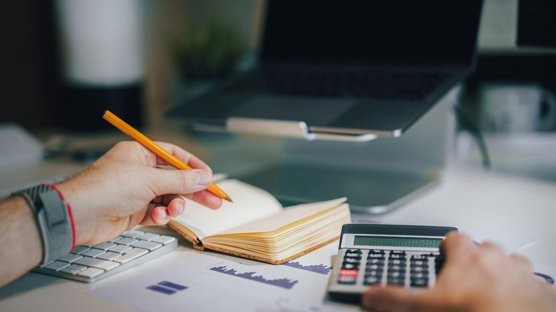 a person sitting at a desk with a calculator and a notebook